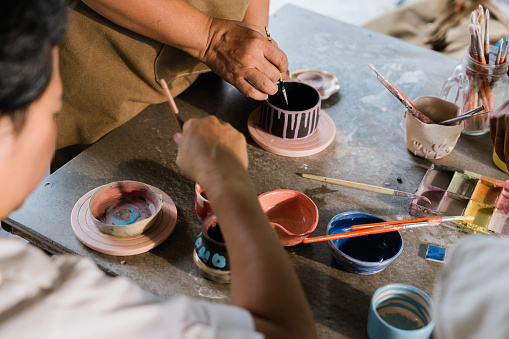 Senior Woman hands painting Pottery Ceramics at class