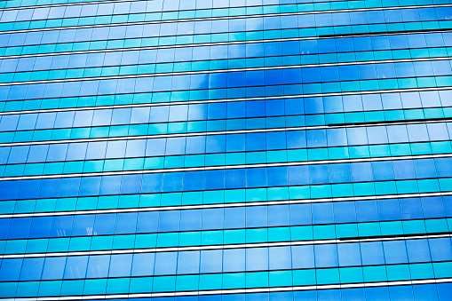 A scene of people in safety equipment cleaning the exterior of a modern glass skyscraper