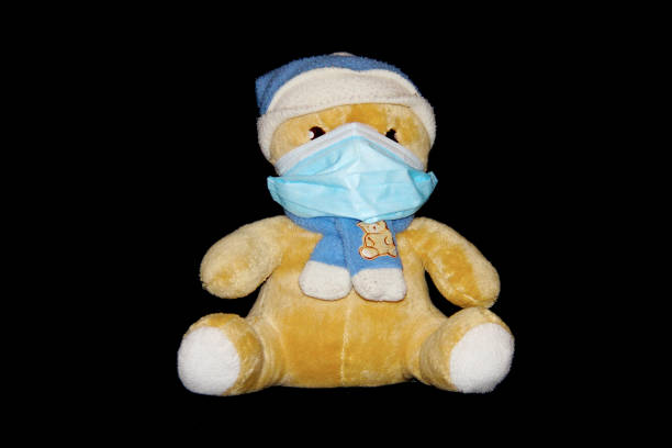 istock Teddy bear wearing mask, scarf and beanie on black background 1767179524