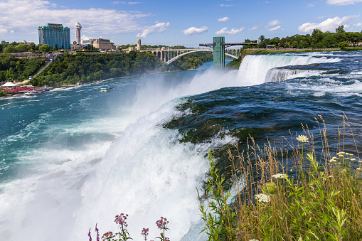 Close-up shot of the American Falls with the Rainbow Bridge in the background in Niagara Falls, NY, USA