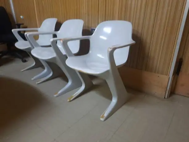 Office Furniture, three old plastic chairs with a futuristic style in front of a 1970s-style wall