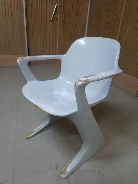 Office Furniture, old plastic chair with a futuristic style in front of a 1970s-style wall