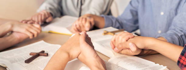 istock Believer hand praying together on bible book while holding hand. Burgeoning 1767201714