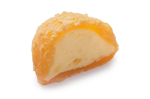 Studio shot of half a mango cheesecake mochi cut out against a white background