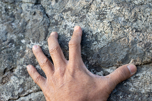 The old man hand was grasping on the rocky surface.