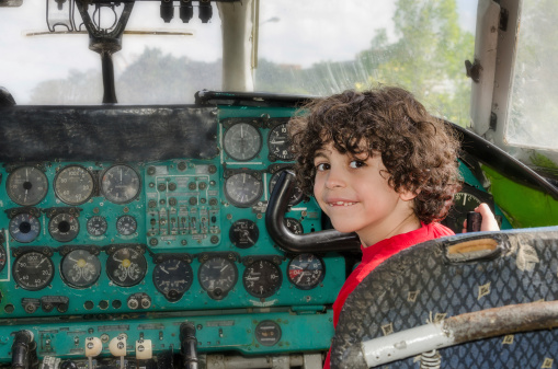 Cute Latin boy playing in the cabin of an old Russian plane