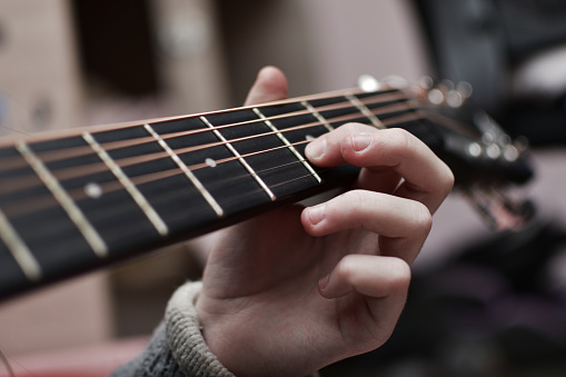 Close-up of a man playing an acoustic guitar. Focus on the fingers.