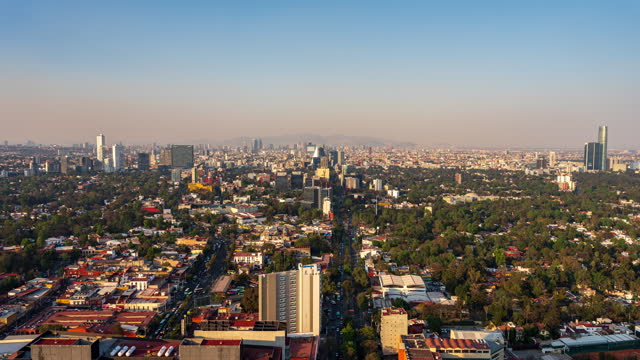 Timelapse of a beautiful sunset in Mexico City, with traffic on Insurgentes Avenue and Revolucion Avenue during rush hour. The skyscrapers on Paseo de la Reforma are visible in the background.