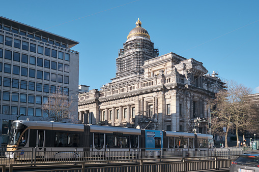 Brussels, Belgium - February 26, 2023: A tram on the tracks in front of Palace of Justice, a large abandoned court building in Brussels, Belgium.