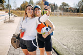 Young woman going on football training with a friend holding exercise mat in hand