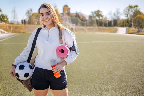 portrait d’une jeune femme préparée pour l’entraînement de football tenant un tapis d’exercice - short de course à pied photos et images de collection