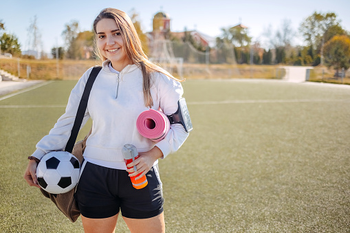 Young adult in sportswear prepared for sport training holding ball in hand