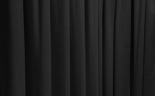 close up dark black curtains use as background. sack cloth texture drape for minimal interior design.  black natural linen drape curtains background. beautiful interior home design backdrop.