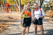 Portrait of young woman going on exercise class with a friend holding exercise mat in hand