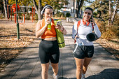 Young woman going on exercise class with a friend holding exercise mat in hand