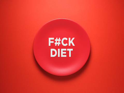 The word Fuck Diet on ceramic red plate over red background. Intuitive eating concept.