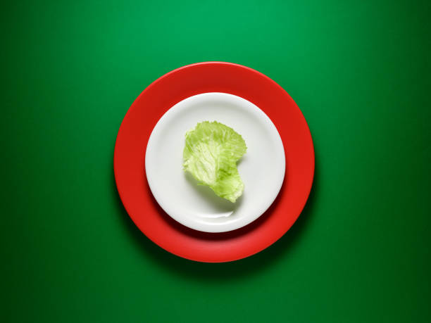 Iceberg lettuce leaf on a plate over green background. Top view, copy space. Creative food concept.