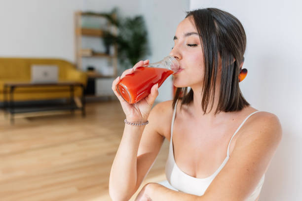 mujer joven hermosa bebiendo jugo de tomate después del entrenamiento físico - juice vegetable fruit vegetable juice fotografías e imágenes de stock