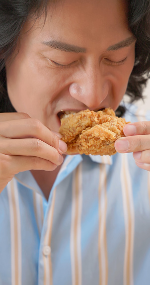close up asian man is eating fried chicken