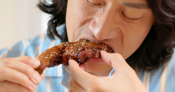 close up asian man is eating roasted chicken