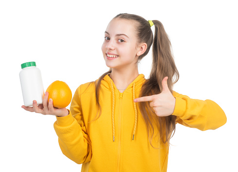 organic food supplement. choice between natural products and pills. presenting vitamin product. child with orange flavored pill. effervescent tablet for kids. girl pointing finger on vitamin c.