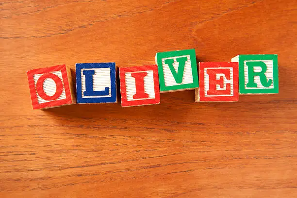 Brightly coloured child's letter blocks on a wooden table spelling out the name Oliver