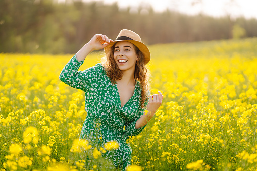 Cute little girl wearing dandelion wreath lying on flower meadow and smiling