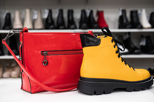 A red women's bag and a yellow shoe on a shelf in an accessories store