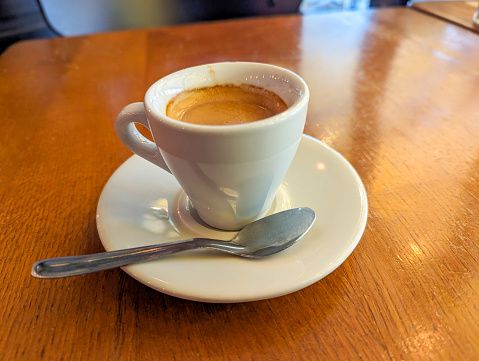 Traditional expresso coffee served in a white cup on the table of a Parisian bistro