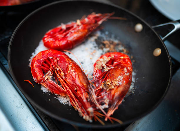 Cooking giant red carabineros prawns on coarse salt