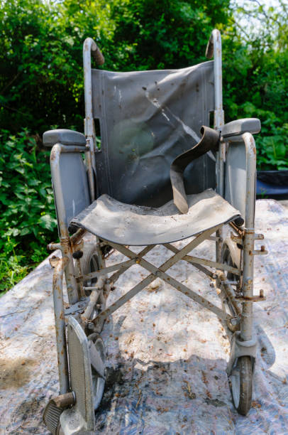 sedia a rotelle abbandonata su un vecchio materasso coperto di terra e ruggine - disablility foto e immagini stock