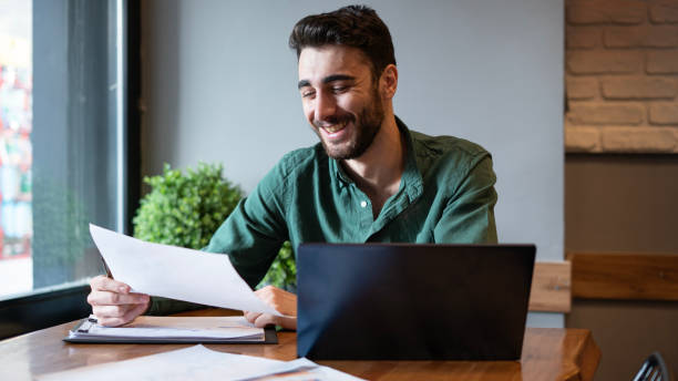 istock Handsome businessman laughing while reviewing financial reports 1767366171