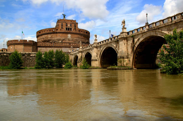 Rome, Italy - May 28, 2019: Photo with a view of the Castel Sant Angelo castle and the Ponte Sant Angelo bridge across the Tiber river against a blue sky with clouds