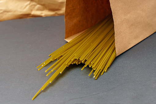 Spaghetti of green peas in a paper bag on a dark background