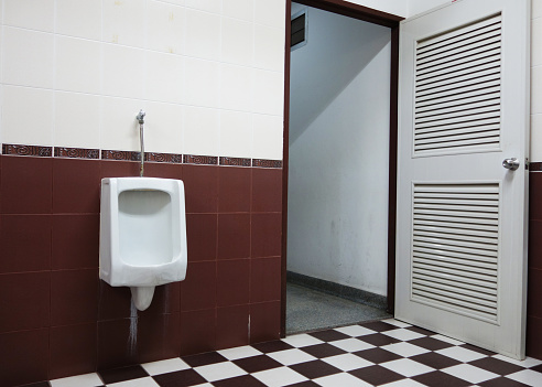 White urinals in the men's bathroom with tiled wall.