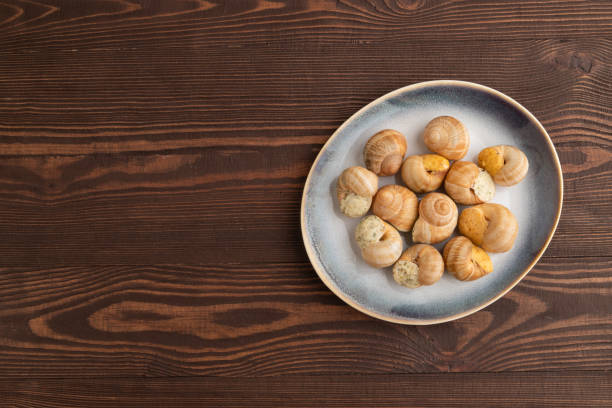 istock Grape (Burgundy) snails with butter and cheese on brown wooden, top view, copy space. 1767385424