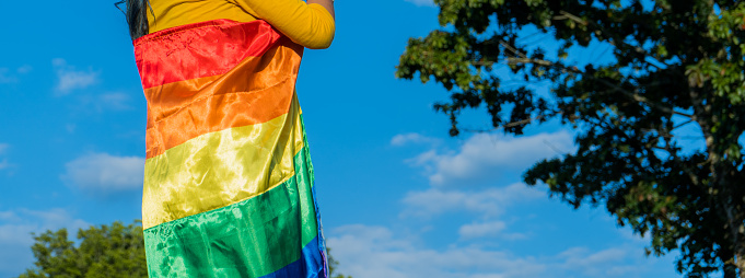 part of a woman rolled up in the open air gay flag.