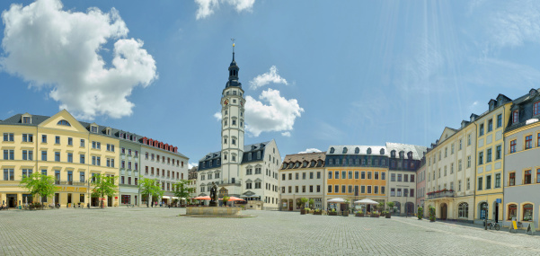 market of Gera - Thuringia, Germany. And the famous town hall. In the middle the fountain called Simson fountain. Around the market are small shops and restaurants. Sun beams visible from the sky and at the houses in the right corner.