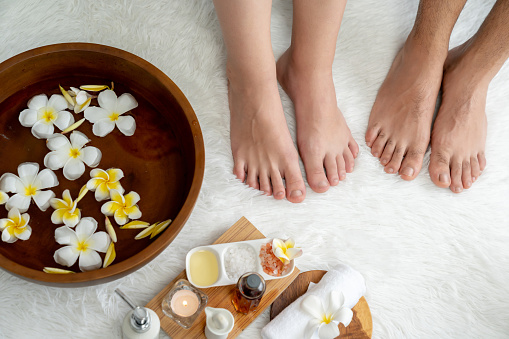 Vertical photo of a woman receiving a reflexology foot massage in a bright clean spa