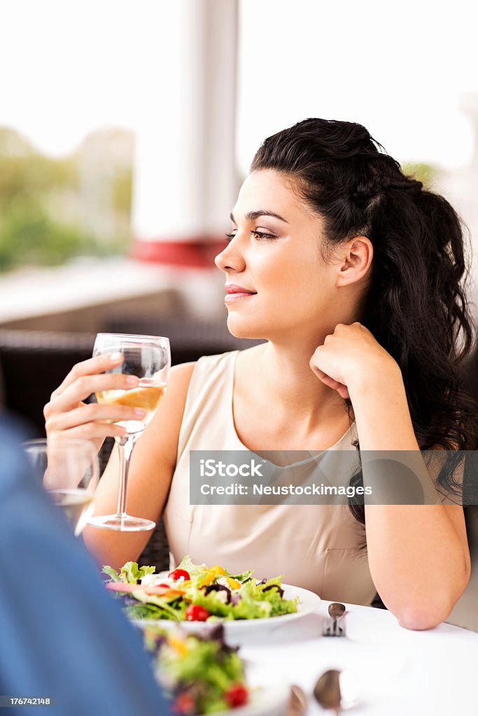 Donna con Bicchiere da vino mentre guardando lontano sul tavolo del ristorante - Foto stock royalty-free di 20-24 anni