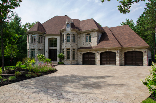 Oak Park, IL, USA - May 23, 2021: A full masonry home with a two car garage, front yard patio, brick paver driveway, and a mixture of brick and stone throughout the exterior.