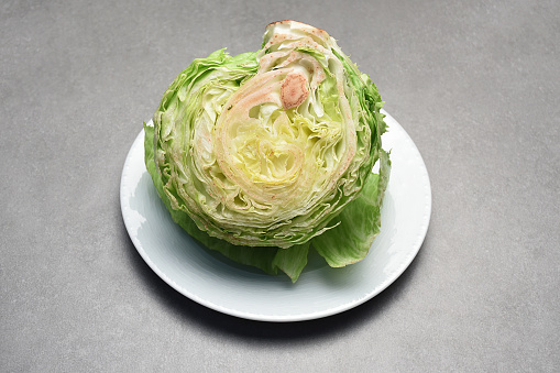 Lettuce vegetable. Half lettuce in a plate on gray table
