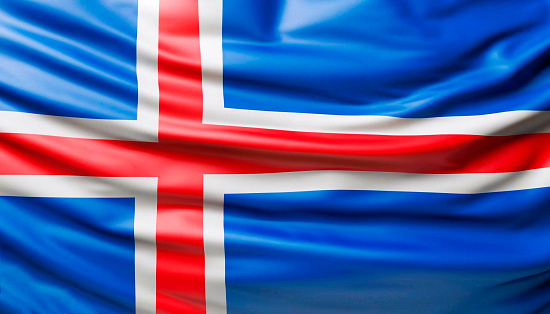 Iceland flag with big folds waving close up under the studio light indoors. The official symbols and colors in fabric banner