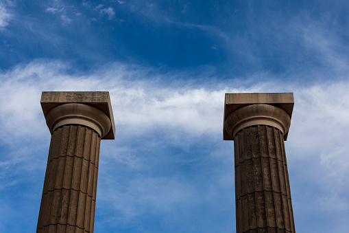 The twin columns, the classic ornamental columns of the Spain Park, the blue sky and a line of clouds passing over them. Quite simetric and contrast photo. On October 17, 2023. In the city of Rosario, province of Santa Fe Argentina.