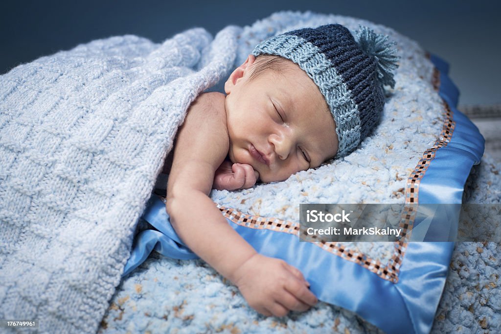Sleeping Newborn Newborn boy asleep on soft blue blankets, wearing a blue knit hat. Babies Only Stock Photo