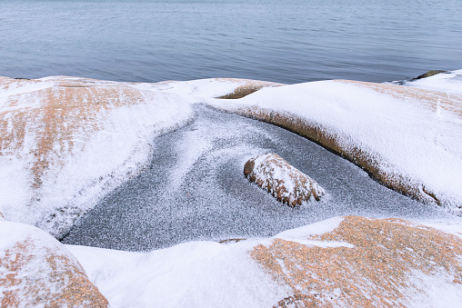 Frozen puddle in the rocks at Swedish winter coastline.
