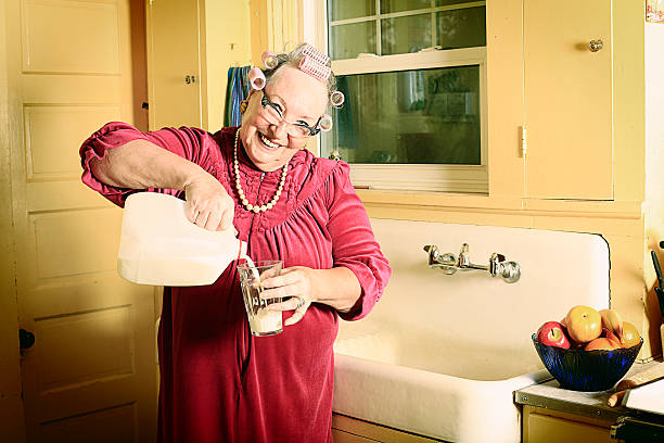 Granny in Kitchen Pouring Milk stock photo