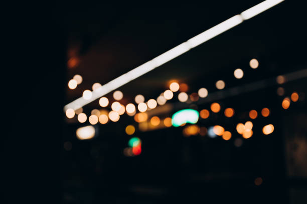 istock Decorative string lights at night time, Defocused Background, night city life backdrop, party time with Yellow bokeh balls. Warm festive bokeh of string lights over an outdoor bar or patio at twilight 1767545641