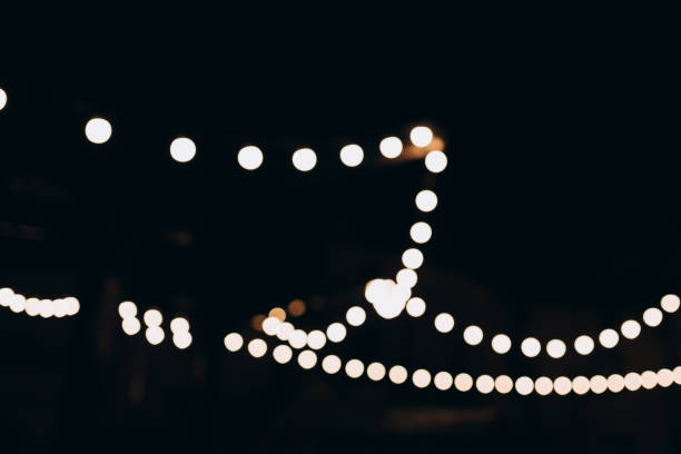 istock Decorative string lights at night time, Defocused Background, night city life backdrop, party time with Yellow bokeh balls. Warm festive bokeh of string lights over an outdoor bar or patio at twilight 1767545669