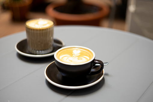 Two cups of coffee with latte art. Table in cafe. Concept of easy breakfast. Small and big size